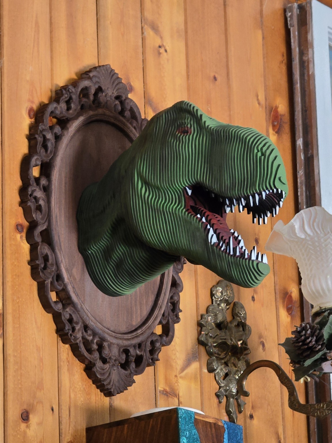 Layered green dinosaur wall art mounted on an ornate frame