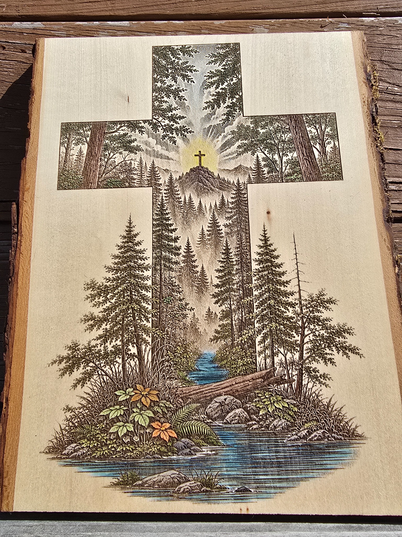 Detailed forest and stream scene engraved into a cross-shaped wood piece